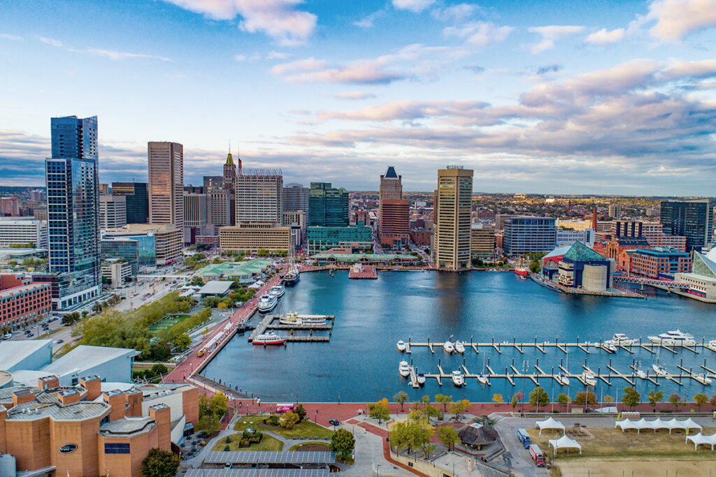 A view of the Baltimore city skyline from the harbor with boats and docks in the water