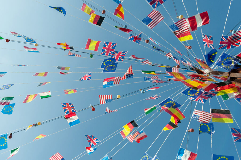 Small flags of many countries on strings radiating from a central pole, viewed from below.