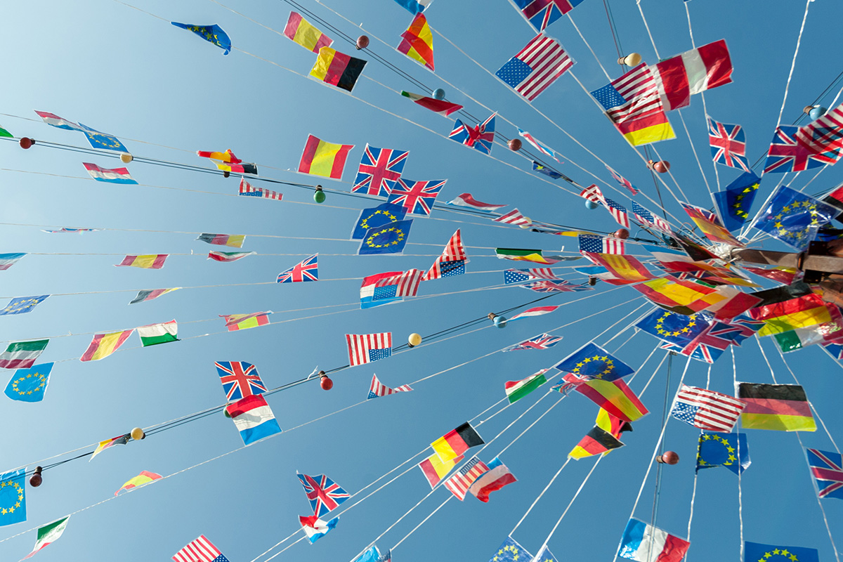 Small flags of many countries on strings radiating from a central pole, viewed from below.