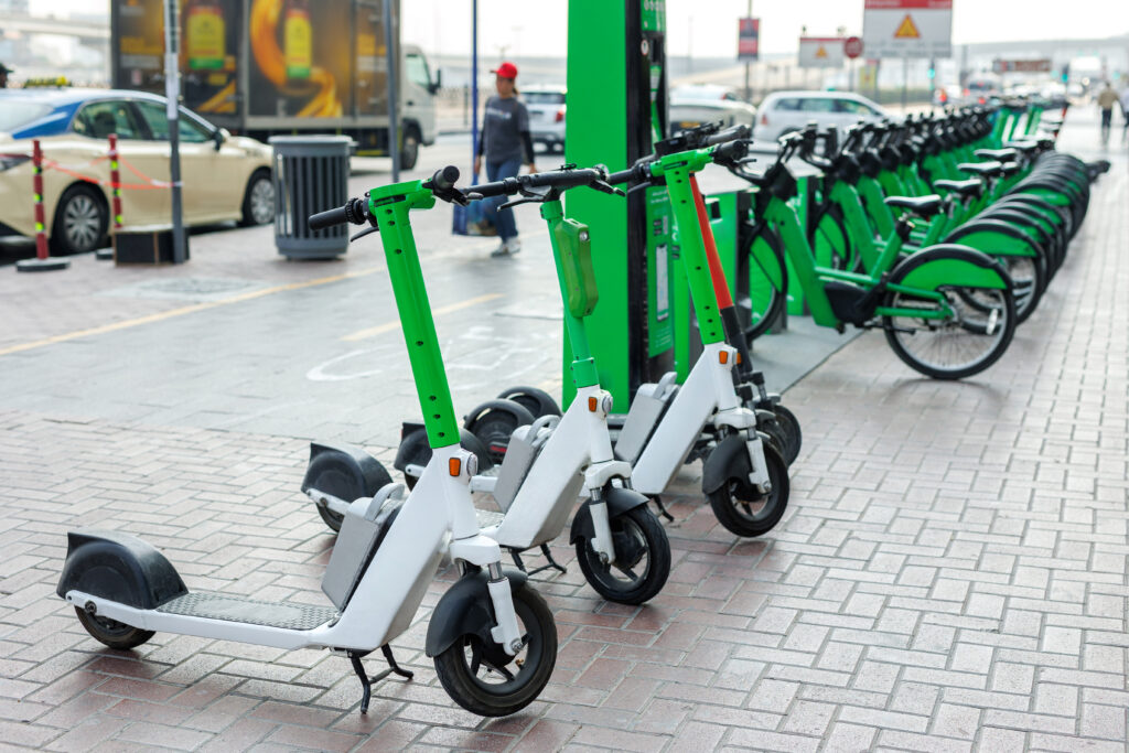 Row of electric scooters and bicycles at a rental station.